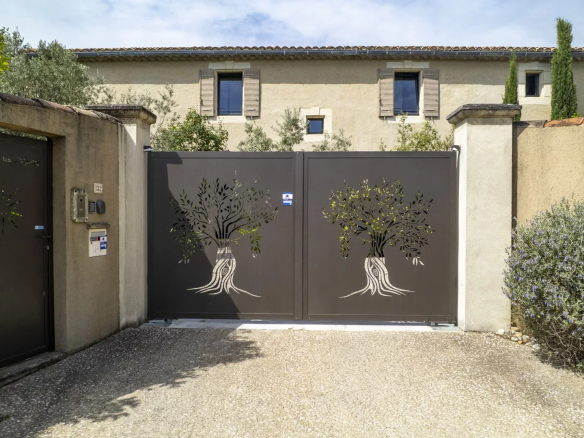 Entrée d'un mas en pierre à Eygalières avec portail décoratif et jardin.