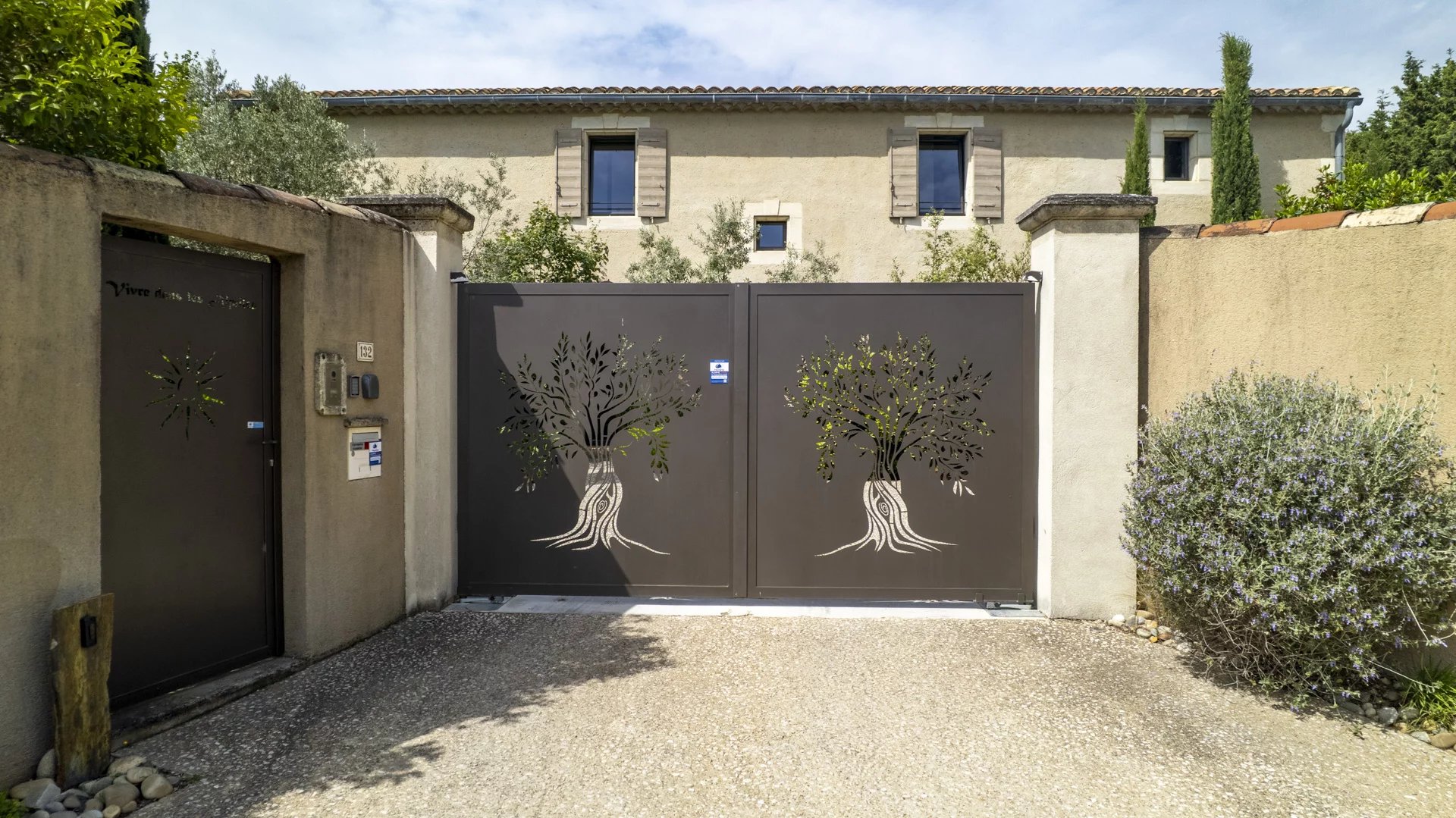 Entrée d’un mas à Eygalières Entrée d'un mas en pierre à Eygalières avec portail décoratif et jardin.