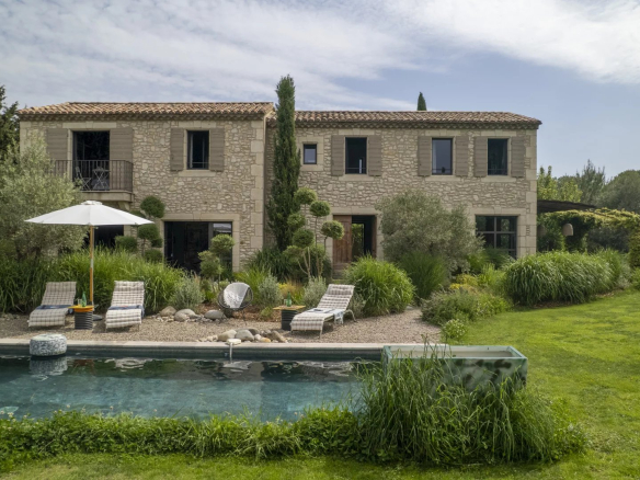 Mas en pierre avec piscine et jardin à Eygalières, entouré de verdure.