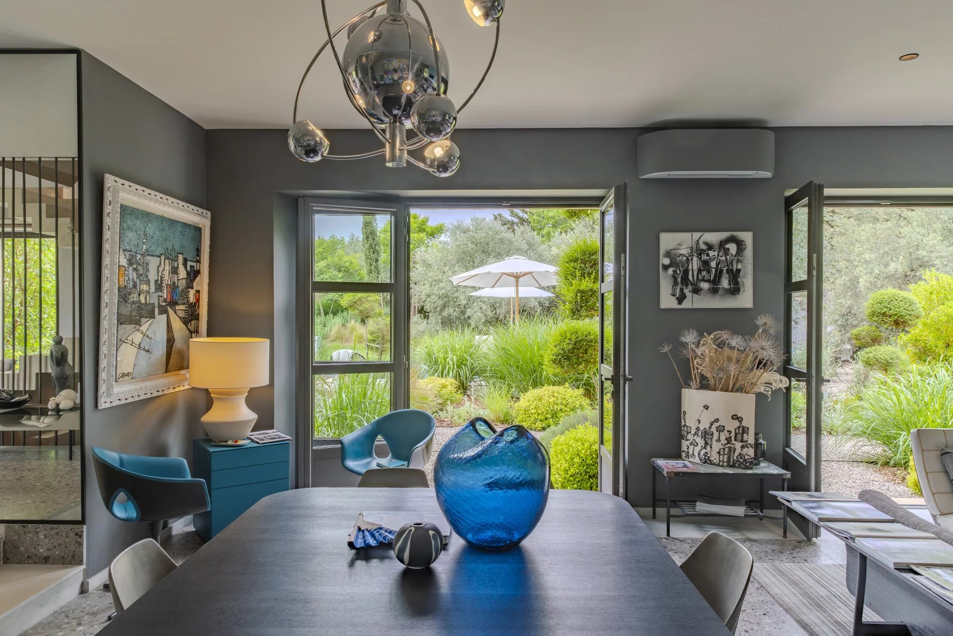 Intérieur d’un mas à Eygalières Intérieur d'une maison moderne avec vue sur un jardin, table à manger, et décor contemporain.