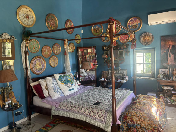 Chambre d'une maison de village avec des murs bleus et des décorations murales colorées.