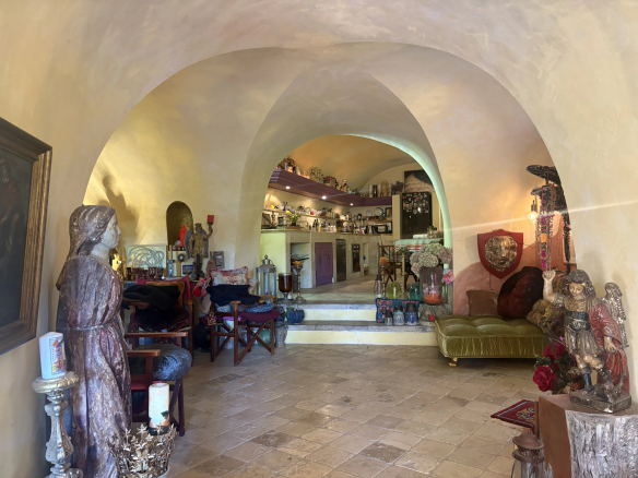 Intérieur d'une maison de village en pierre à Eygalières, avec des arches et des objets décoratifs.