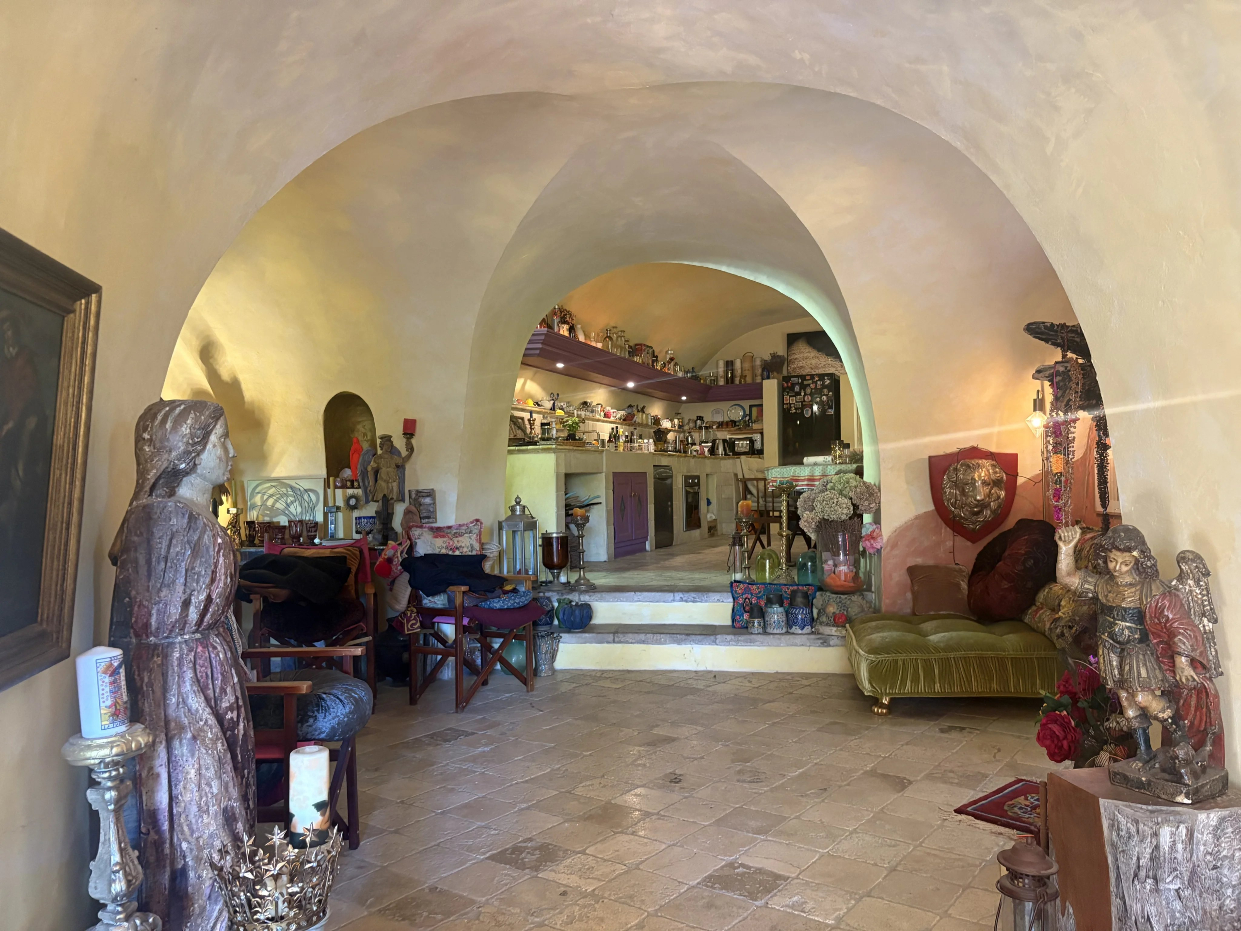 Intérieur d’une maison de village à Eygalières Intérieur d'une maison de village en pierre à Eygalières, avec des arches et des objets décoratifs.