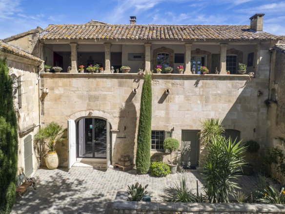 View of a 17th century stone house with courtyard and vegetation, located in Paradou.
