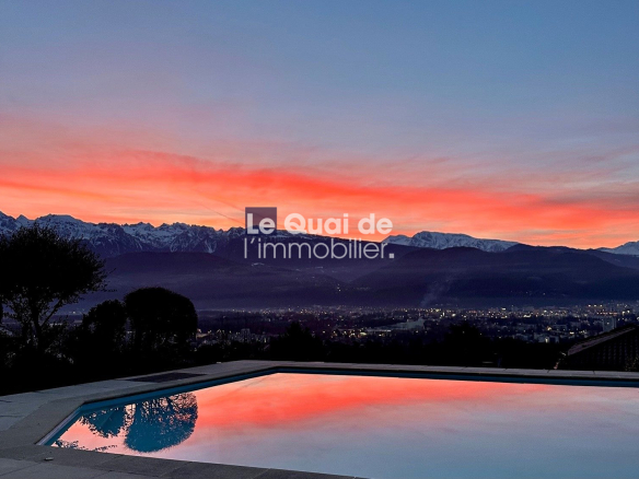 Sunset over snow-capped mountains with a reflecting pool in the foreground; watermark reads 'Le Quai de l’immobilier'