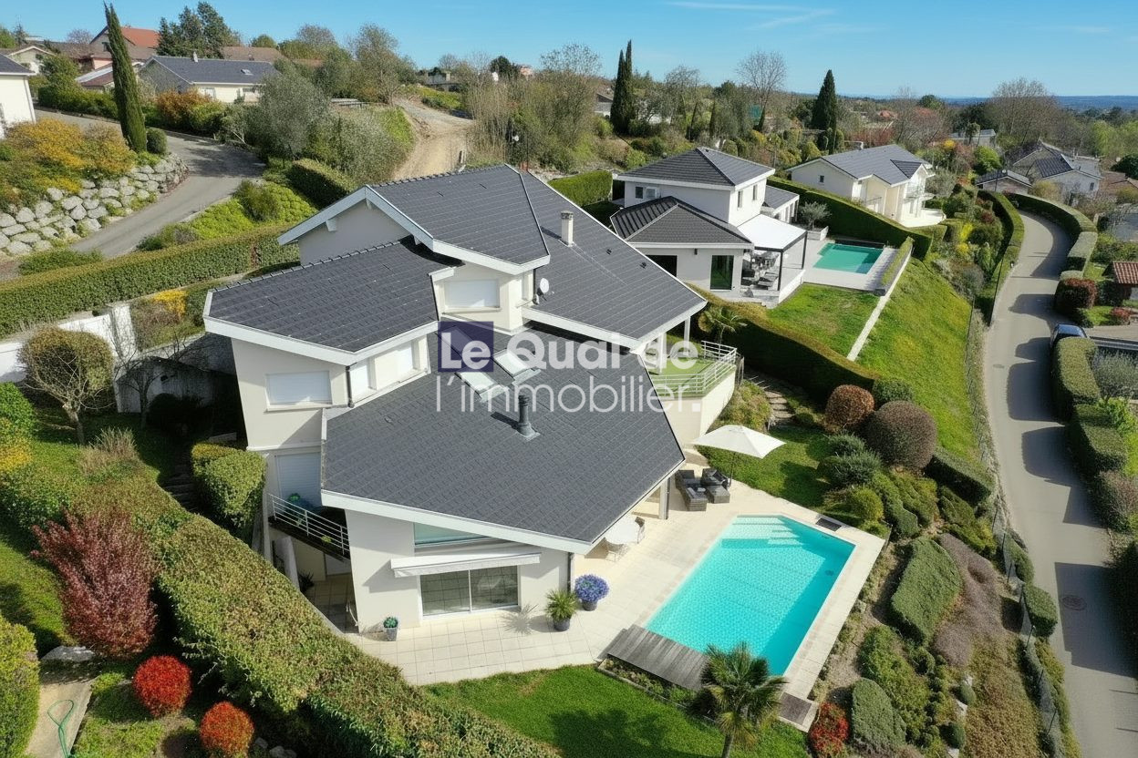 1772460981_VM8231_26_original A modern white villa with a dark tiled roof and a rectangular turquoise pool in a landscaped hillside yard in bright daylight, aerial view.