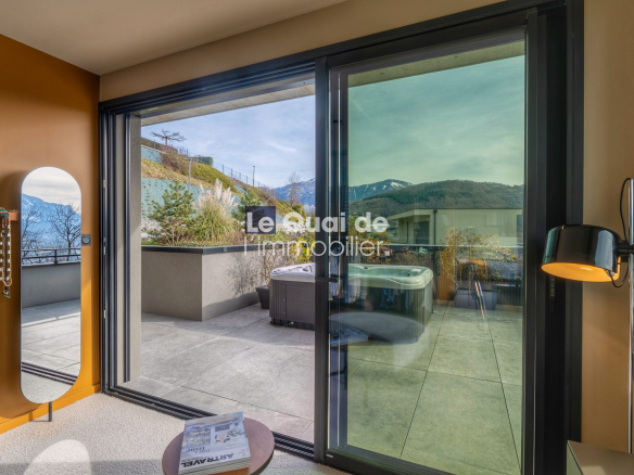 Modern interior with an orange wall, a tall oval mirror and jewelry hooks on the left, sliding glass doors opening to a terrace with a hot tub and mountain views outside.
