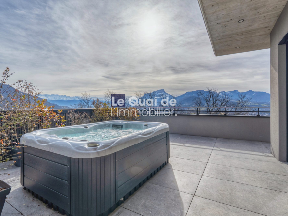 Modern balcony with a hot tub overlooking a mountain range under a cloudy sky.