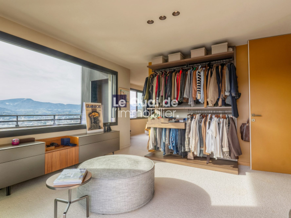 Spacious walk-in closet with double hanging racks full of clothes, a low cabinet, ottoman, and a window with mountain view.