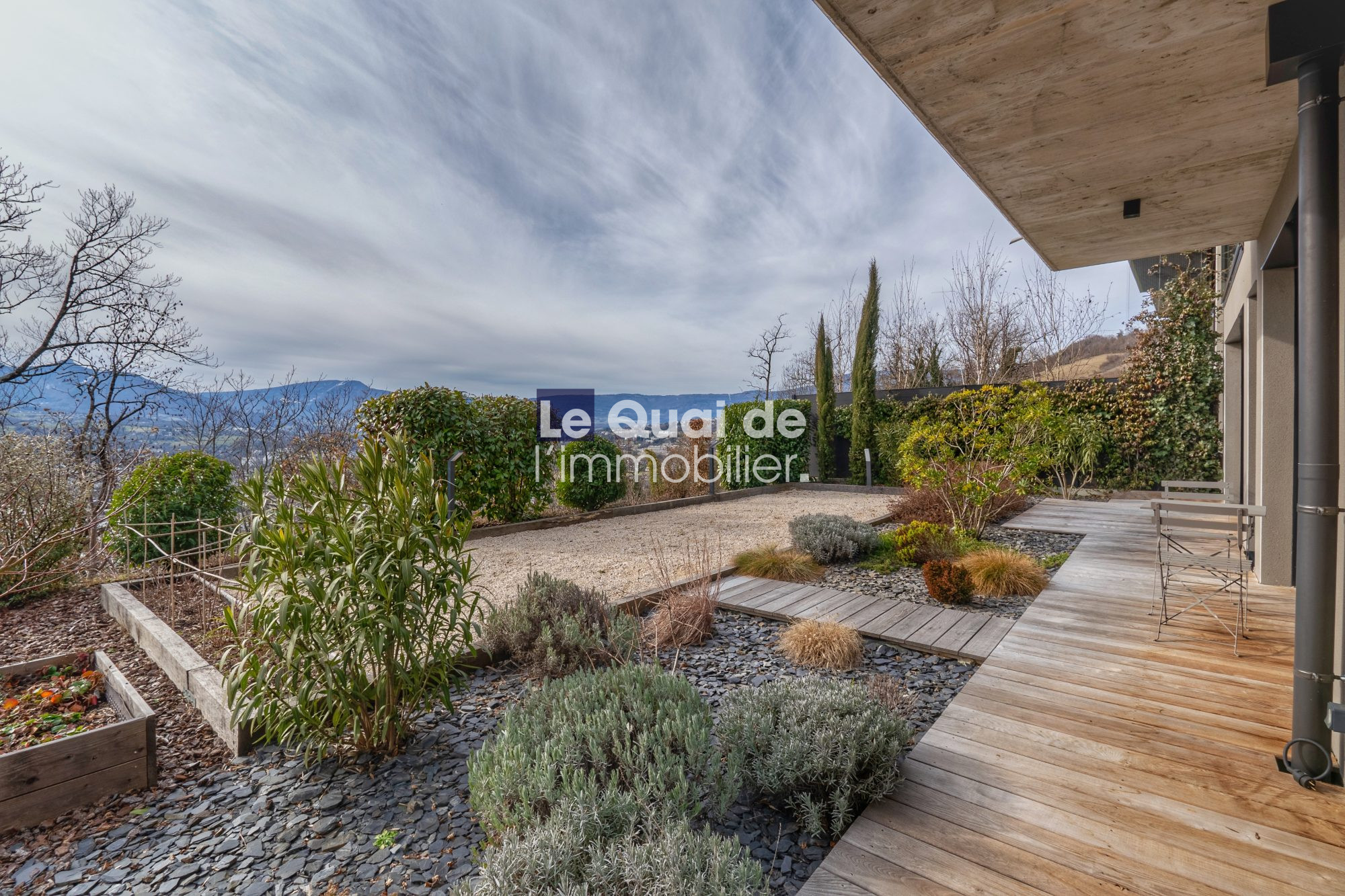 1771603330_VM8233_23_original Wooden deck patio with a landscaped garden and distant mountains along the hedge line.