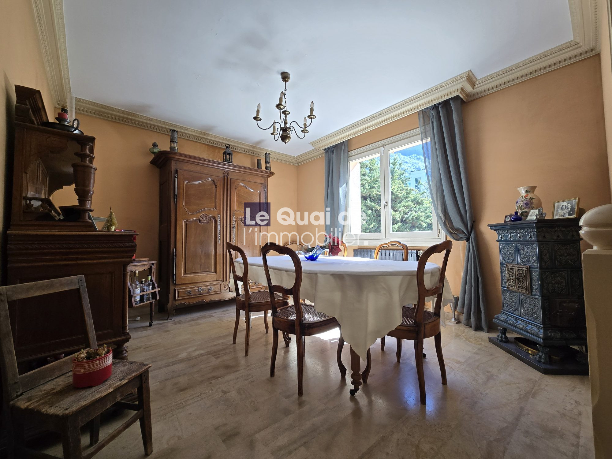 Traditional dining room with antique wooden hutch, round table, and chairs under a chandelier.