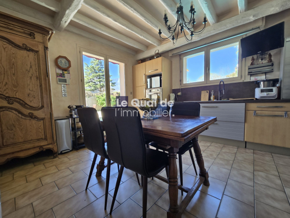 Cozy kitchen with a wooden dining table and four black chairs under a chandelier, large windows and a garden view outside civil doors.