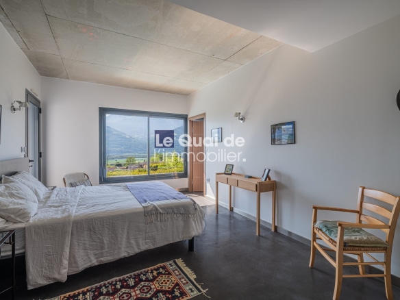 Chambre d'une villa d'architecte avec vue sur les montagnes, mobilier moderne et lumière naturelle.