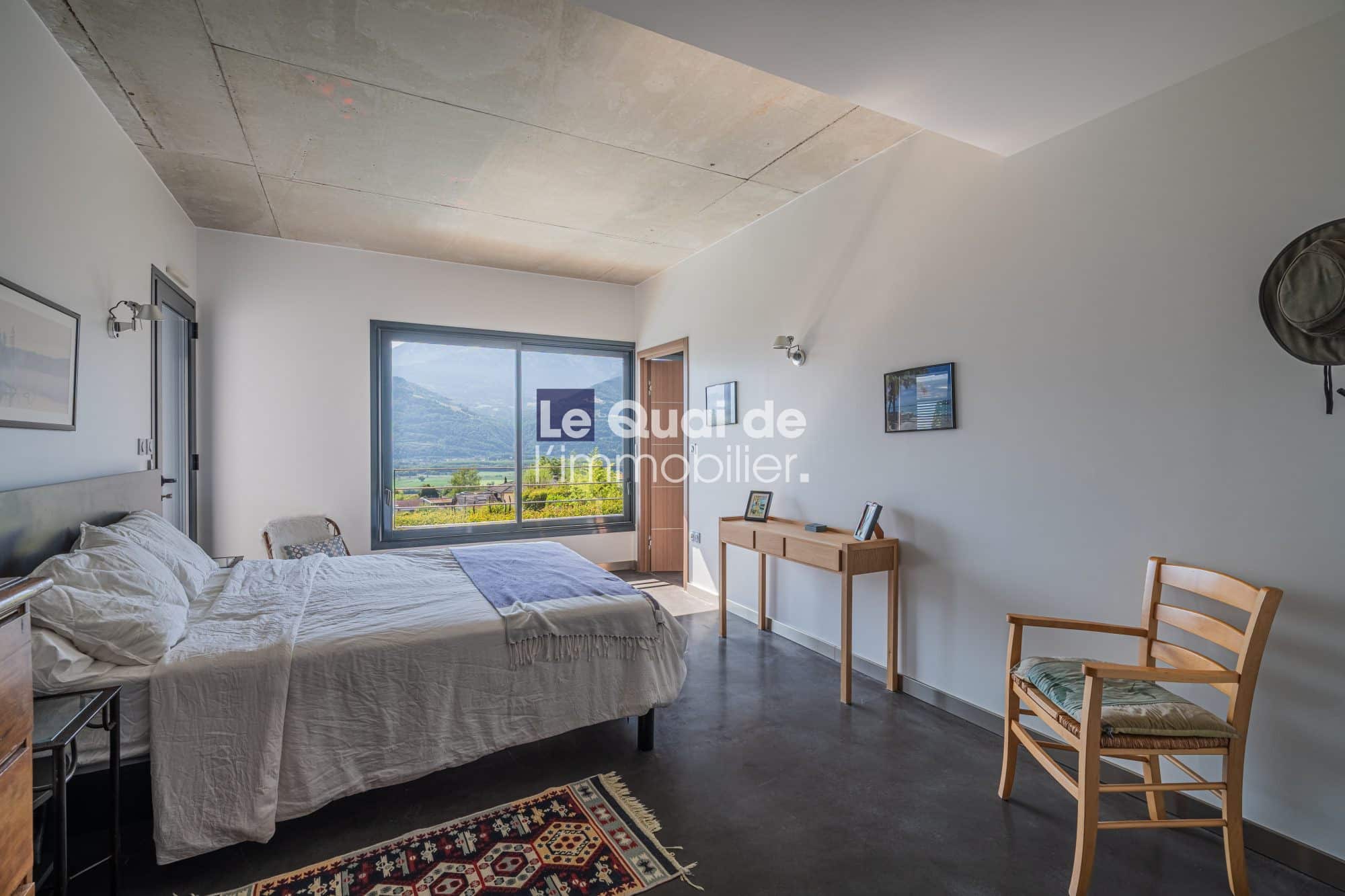 Chambre d'une villa d'architecte avec vue sur les montagnes, mobilier moderne et lumière naturelle.