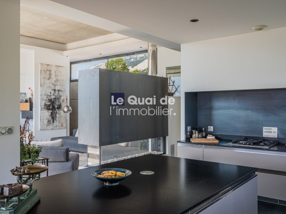 Intérieur d'une villa moderne avec cuisine ouverte et salon, vue sur piscine et terrasse.