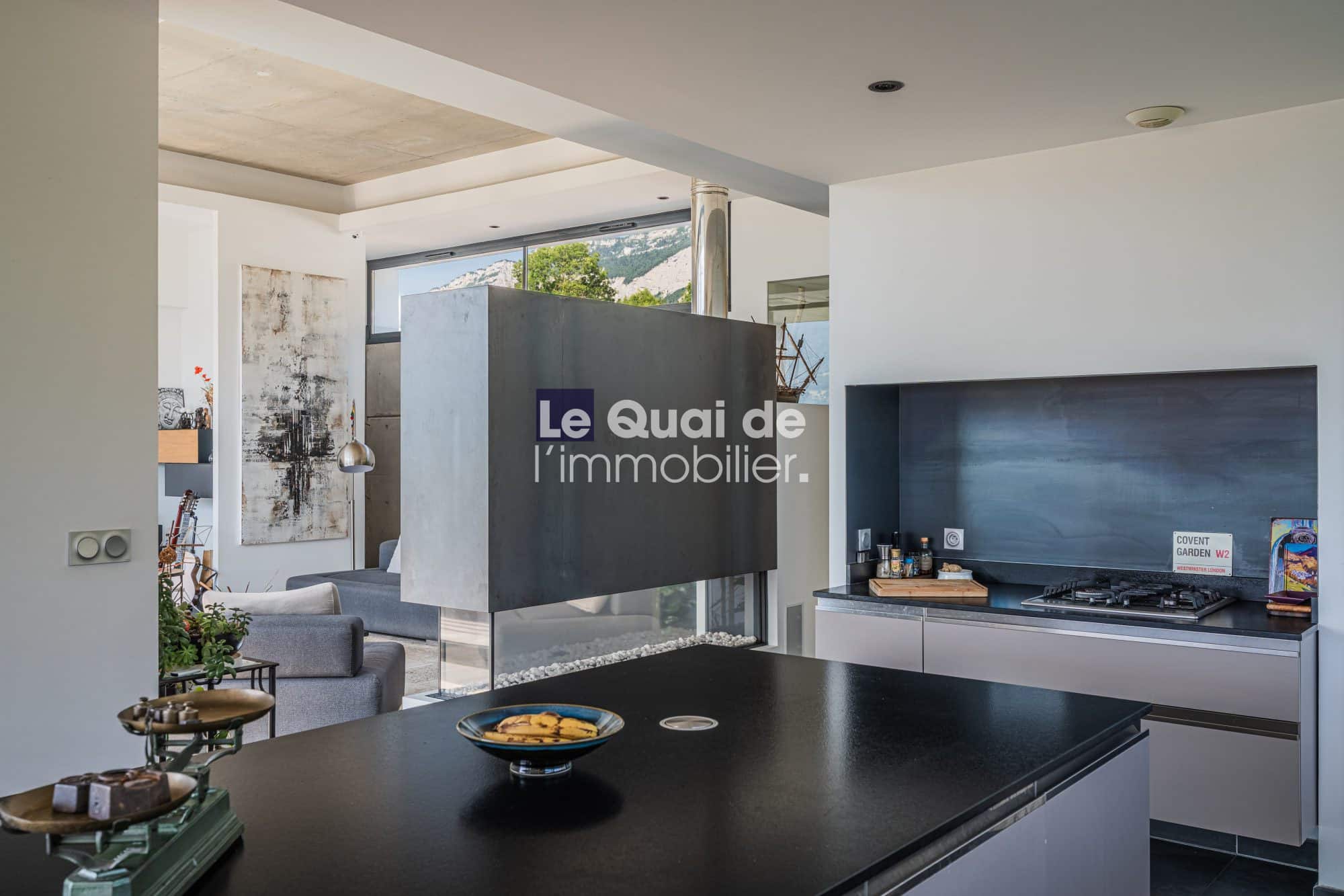 Intérieur d'une villa moderne avec cuisine ouverte et salon, vue sur piscine et terrasse.