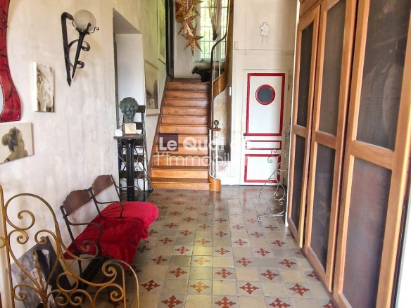 Intérieur d'une maison de maître avec carrelage ancien et escalier en bois.