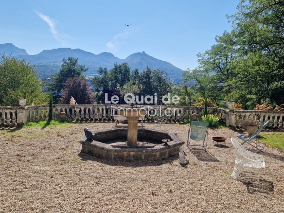 Vue d'un jardin avec fontaine et chaises, montagnes en arrière-plan à Chambéry.
