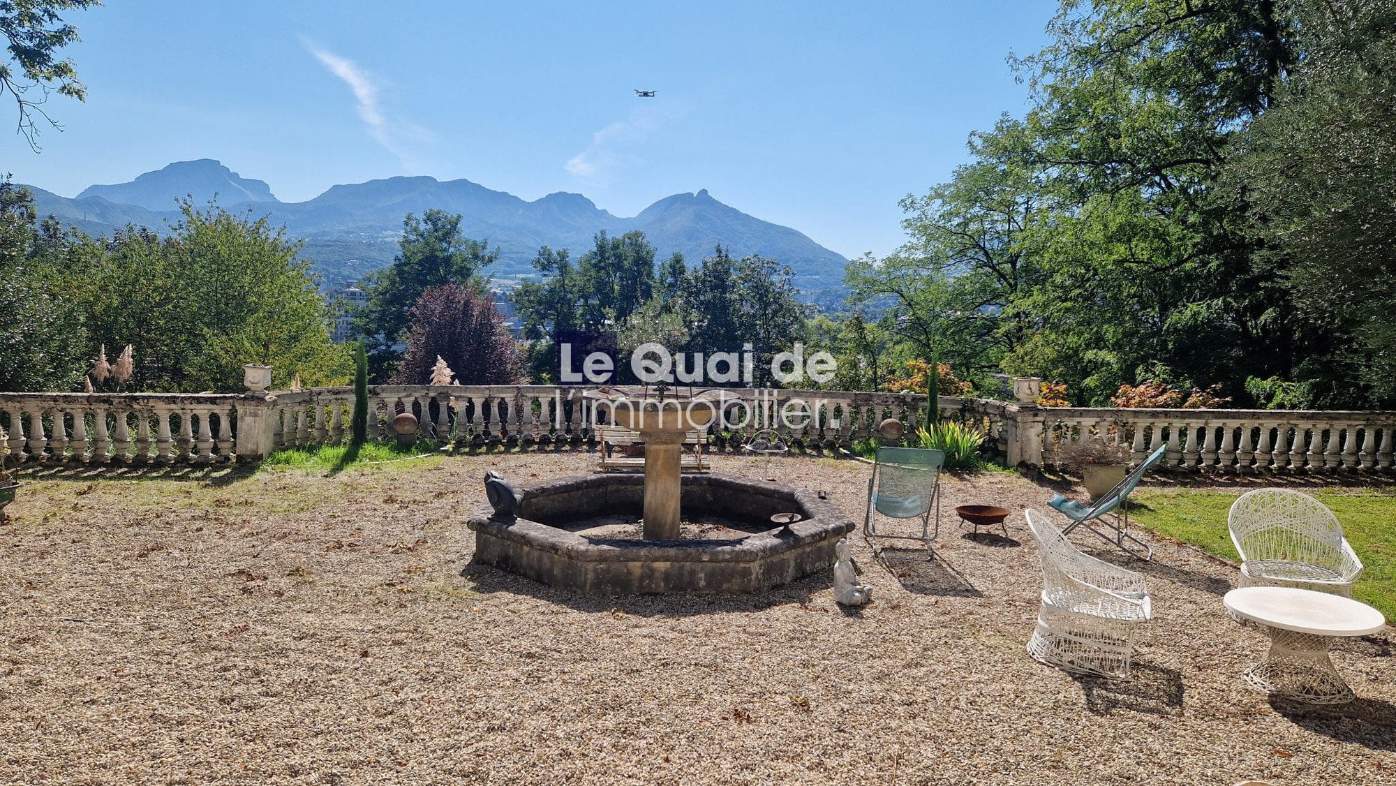 Vue d'un jardin avec fontaine et chaises, montagnes en arrière-plan à Chambéry.