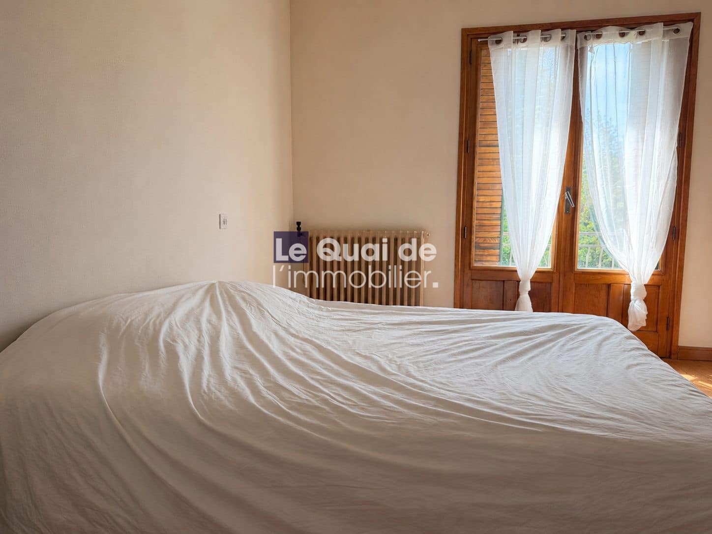 Chambre avec lit et fenêtres donnant sur l'extérieur dans une maison à vendre.
