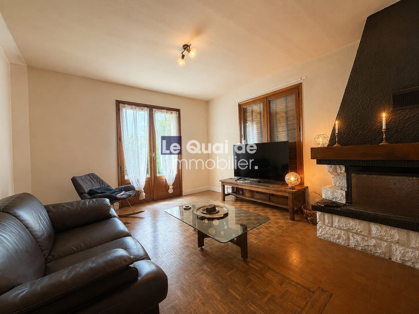 Intérieur d'une maison à vendre à Drumettaz-Clarafond, salon avec canapé et télévision.