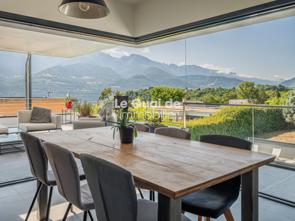 Interior of a modern villa with mountain views, wooden table and large bay windows.