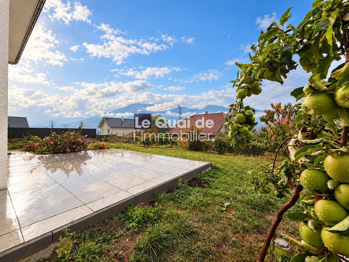 Jardin avec terrasse à Cruseilles Vue d'un jardin avec terrasse en pavés et arbres fruitiers, sous un ciel nuageux à Cruseilles.