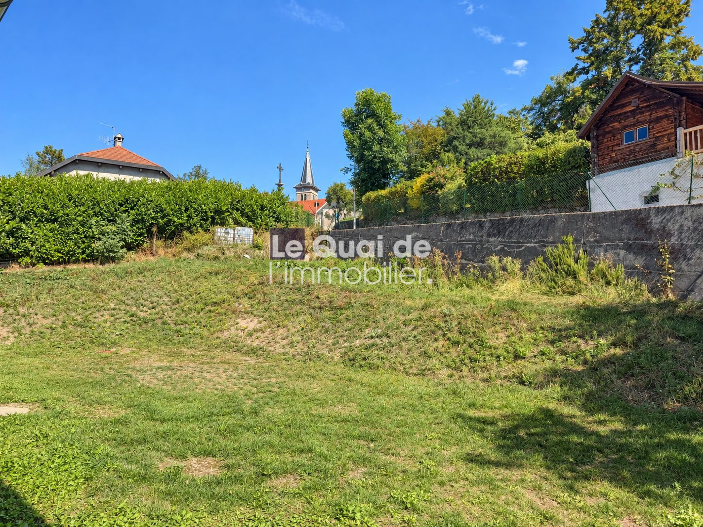 Plot of 1,388 m² with views of houses in Nâves-Parmelan, blue sky and greenery.