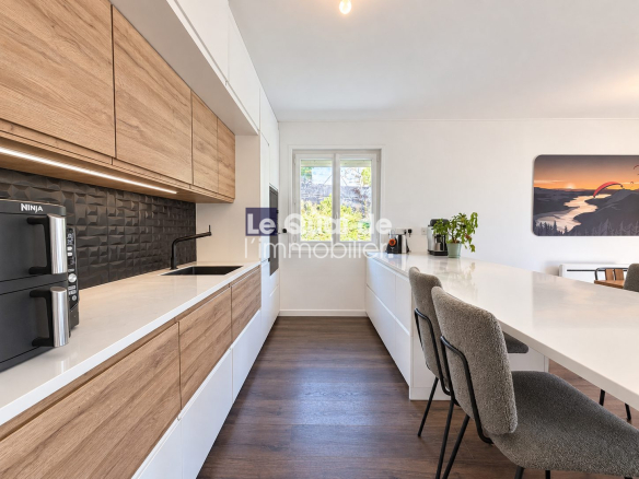 Modern kitchen with wooden furniture and white countertop in a house in Nâves-Parmelan.
