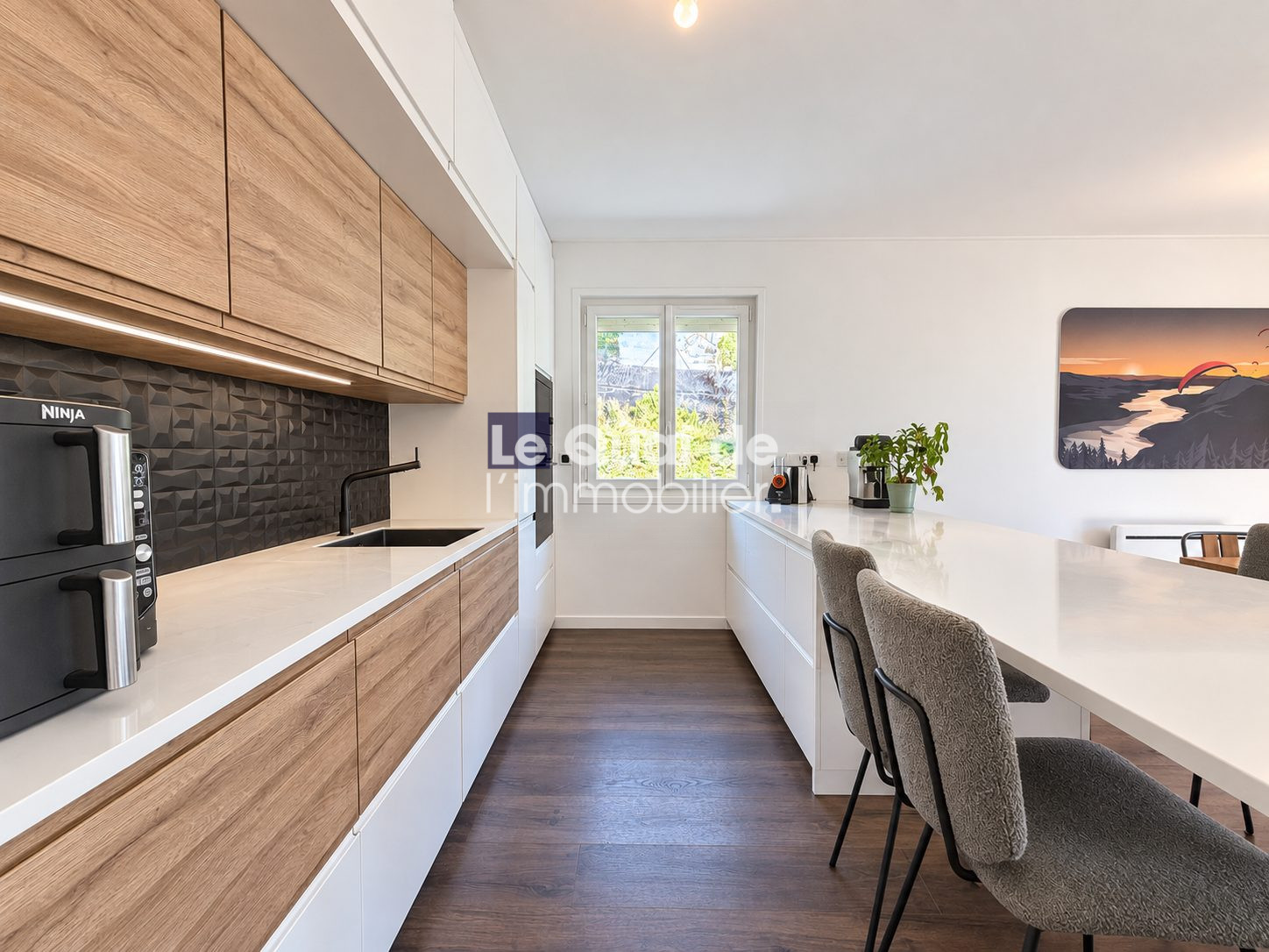 Modern kitchen with wooden furniture and white countertop in a house in Nâves-Parmelan.