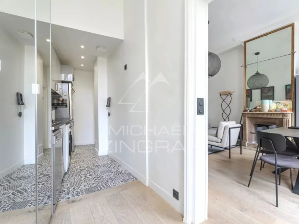 Intérieur d'un appartement rénové à Paris, avec un couloir menant à un salon et une cuisine.