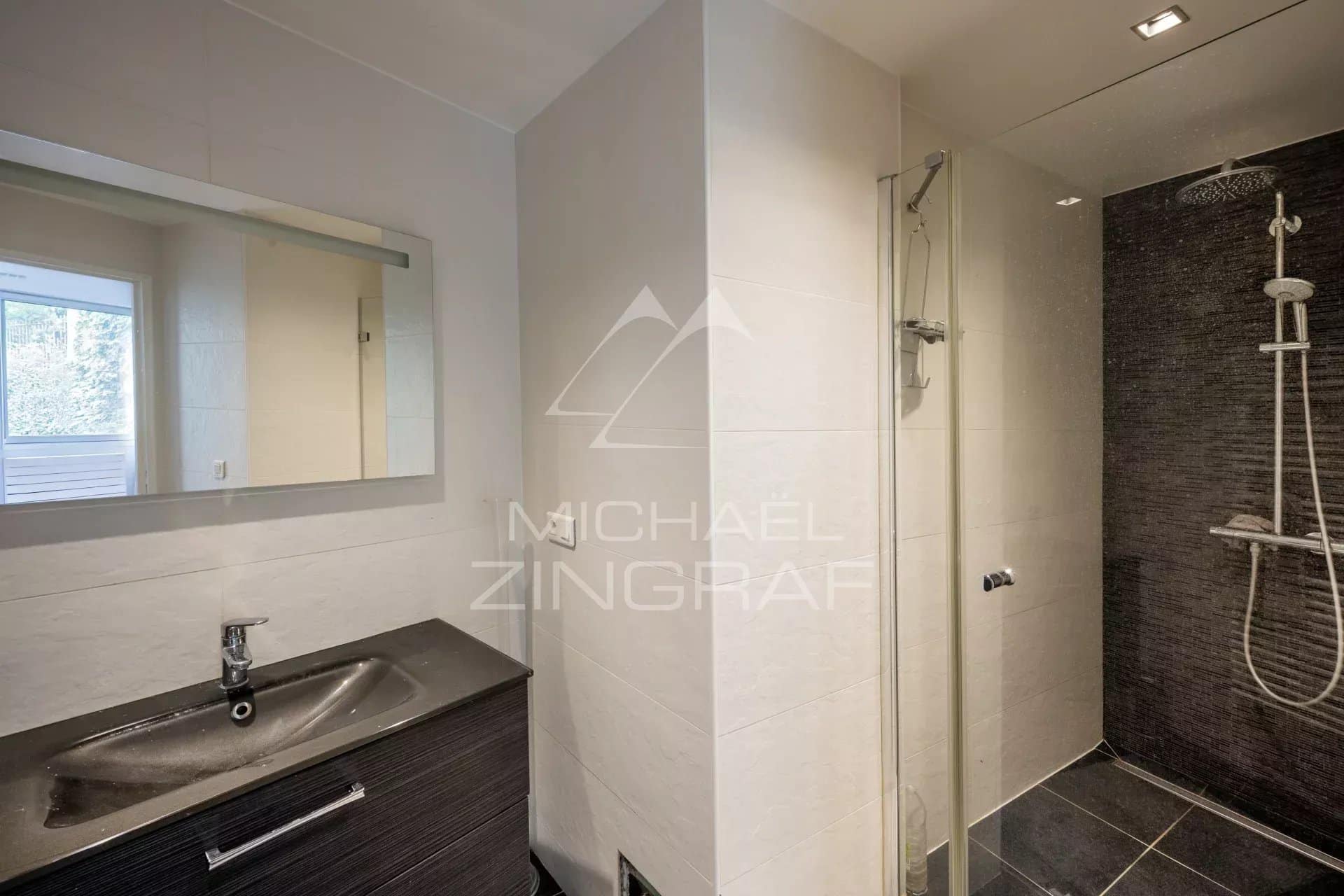 Salle de bain moderne avec douche et lavabo dans un appartement à Neuilly-sur-Seine.