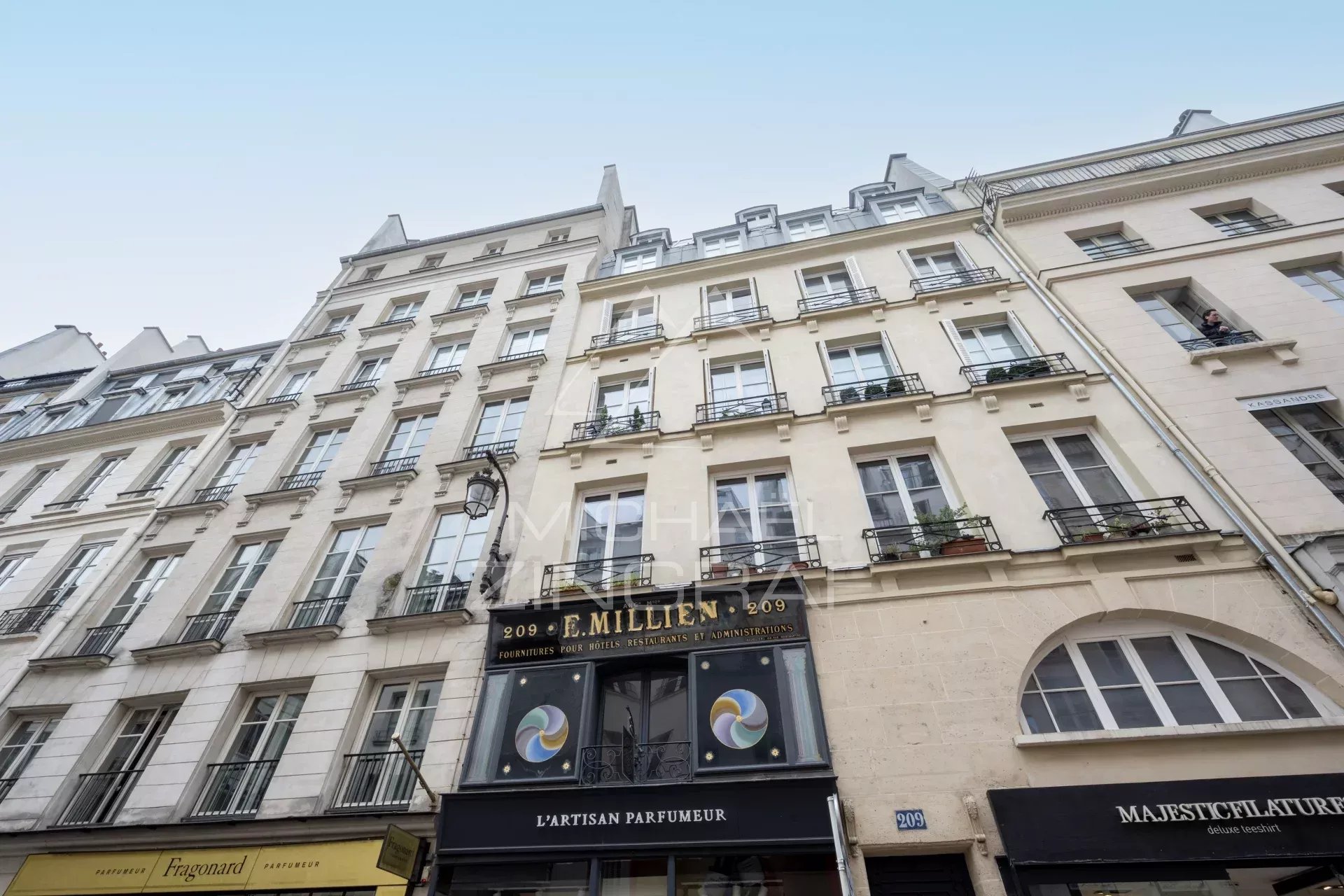 Façade d'un immeuble sur la rue Saint Honoré à Paris, avec boutiques au rez-de-chaussée.