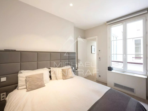 Chambre d'un appartement moderne avec lit double et fenêtre à Paris 1er.
