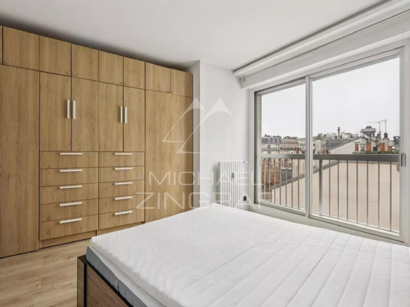 Chambre avec placards intégrés et vue sur balcon dans un appartement à Paris 16ème.