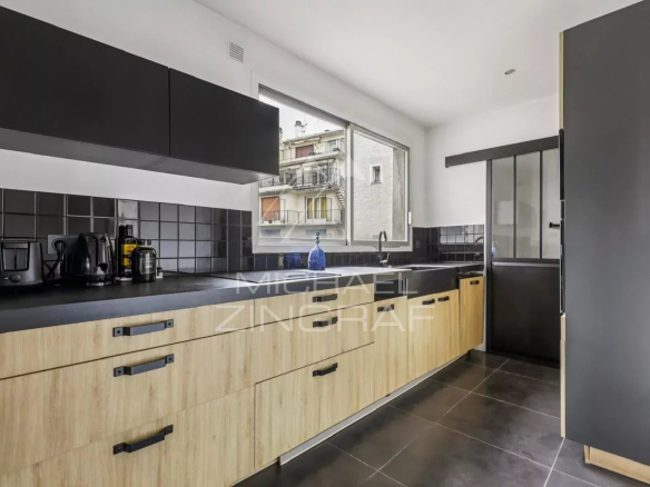 Cuisine moderne avec meubles en bois et noir, fenêtre donnant sur l'extérieur.