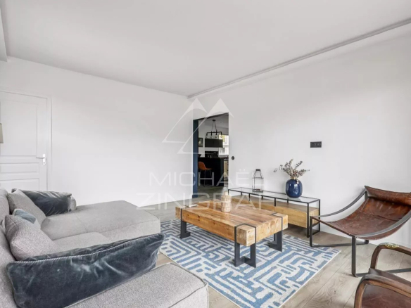 Salon d'un appartement à vendre à Paris 16ème avec canapé, table basse en bois et décoration moderne.
