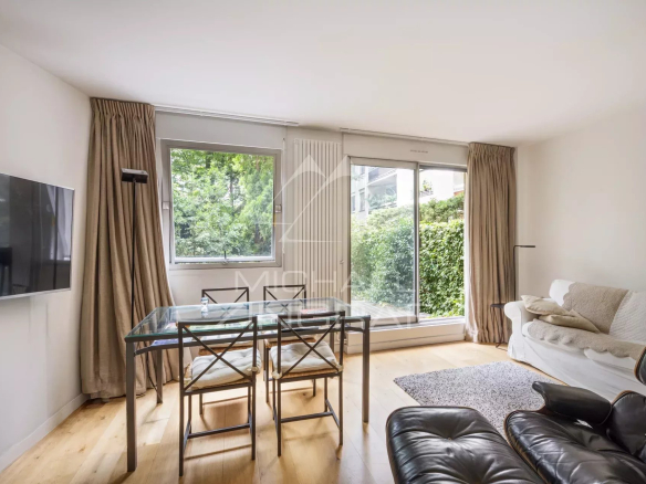 Intérieur d'un appartement moderne avec salon, table à manger et accès au jardin.