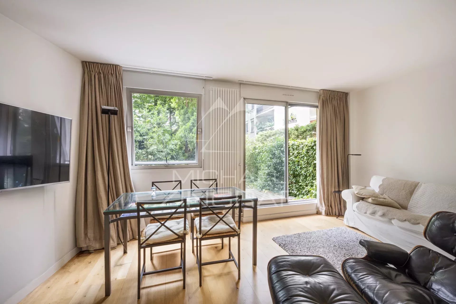 Appartement 2 pièces à Neuilly-sur-Seine Intérieur d'un appartement moderne avec salon, table à manger et accès au jardin.