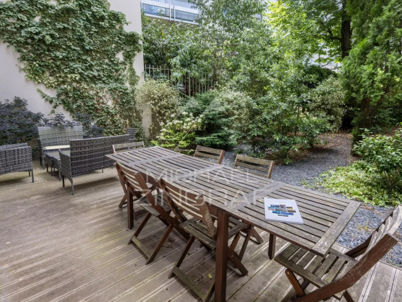 Terrasse en bois avec mobilier de jardin entourée de verdure dans un appartement à Neuilly-sur-Seine.