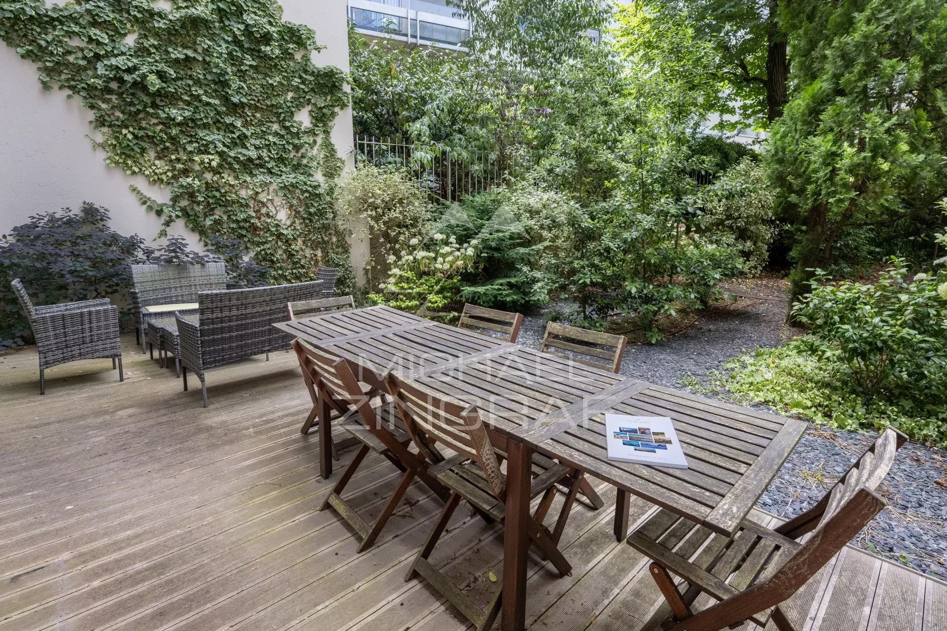 Terrasse et jardin privatif à Neuilly-sur-Seine Terrasse en bois avec mobilier de jardin entourée de verdure dans un appartement à Neuilly-sur-Seine.