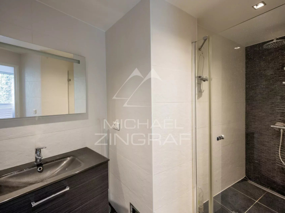 Salle de bain moderne avec douche et lavabo dans un appartement à Neuilly-sur-Seine.