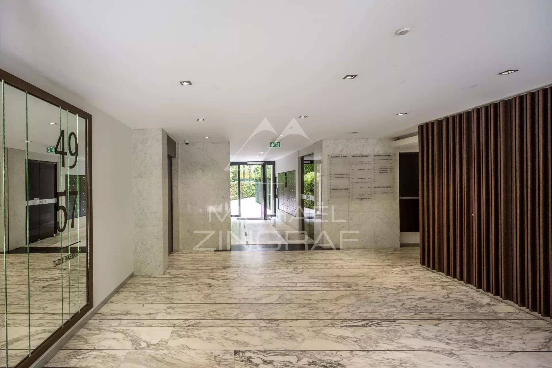 Hall d’entrée d’un immeuble à Neuilly-sur-Seine Hall d'entrée d'un immeuble moderne avec sol en marbre et murs en pierre.