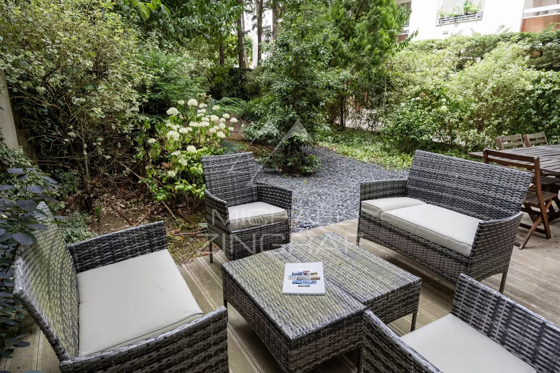 Terrasse et jardin privatif à Neuilly-sur-Seine Terrasse et jardin privatif d'un appartement à Neuilly-sur-Seine, avec mobilier de jardin en osier.
