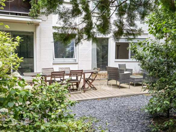 Terrasse et jardin privatif d'un appartement à Neuilly-sur-Seine, entourés de verdure.