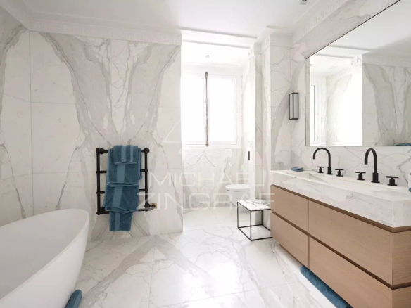 Salle de bain moderne avec baignoire, lavabo double et décor en marbre.