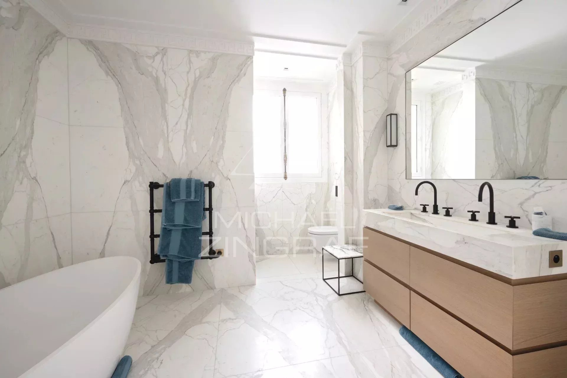 Salle de bain d’un appartement à Paris Salle de bain moderne avec baignoire, lavabo double et décor en marbre.