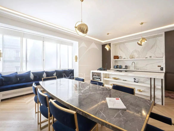 Intérieur d'un appartement moderne avec une table à manger en marbre et un coin salon lumineux.