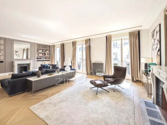 Intérieur d'un appartement rénové avec salon spacieux et lumineux, parquet en bois et grandes fenêtres.