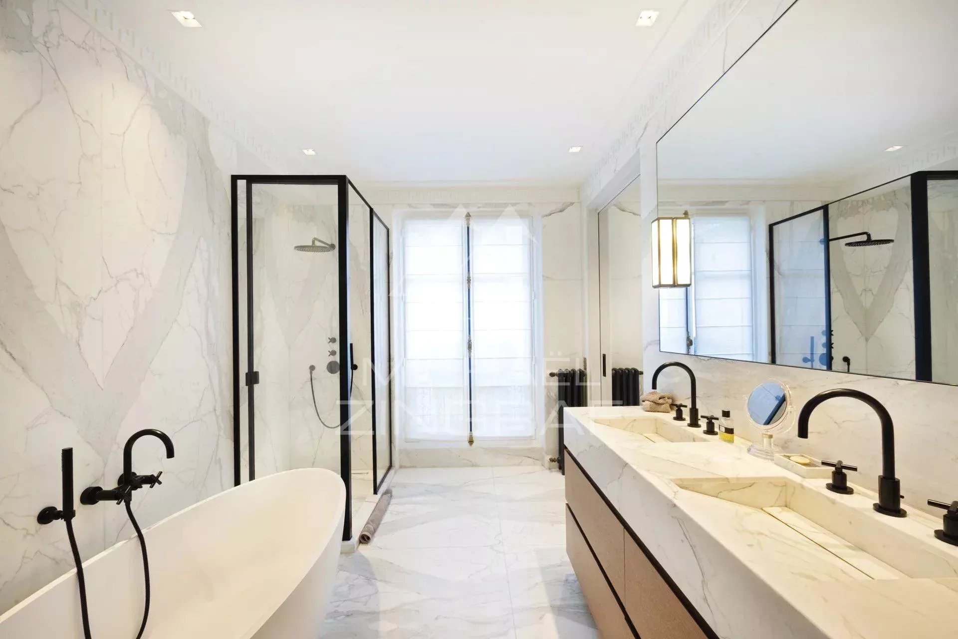 Salle de bain d’un appartement rénové à Paris Salle de bain moderne avec baignoire, douche et double vasque en marbre